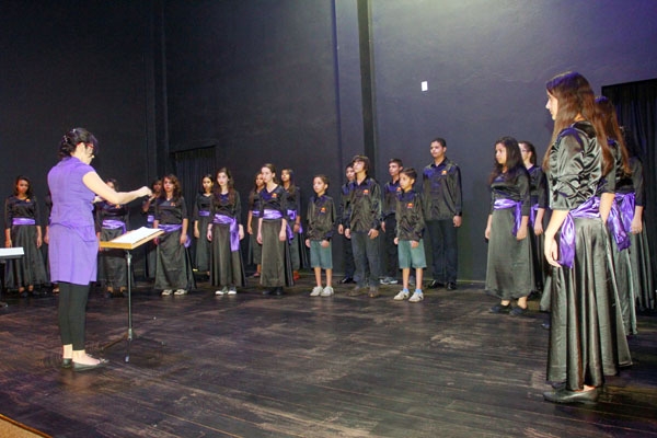 No palco do Teatro de Bolso, a maestrina Raquel Castro prepara os garotos do Projeto Guri para apresentação no Chile